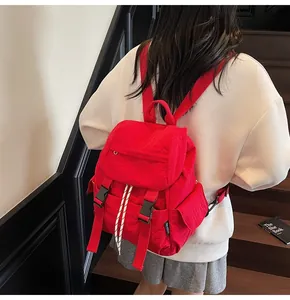 Detail of red nylon backpack showing buckle closure and drawstring texture on stairs