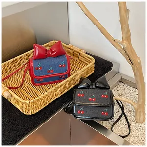 Detail of denim mini crossbody bags with cherry embroidery and glossy leather bows