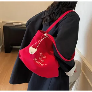 Detail of red canvas tote bag featuring white embroidery and drawstring closure