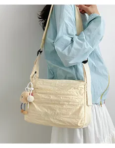 Detail der beigefarbenen Crossbody-Tasche aus Faltennylon mit Stickerei und Bär
