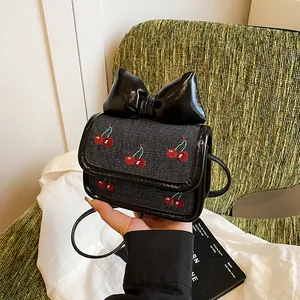 Mini denim crossbody bag with cherry embroidery and oversized black bow decor