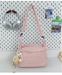 Detailansicht der pinkfarbenen Nylon-Umhängetasche mit Bärenanhänger und Stickerei