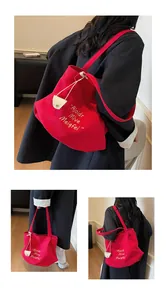 Detail of red canvas tote bag with white embroidery and leather buckle straps