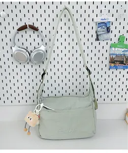 Detail der salbeigrünen Nylon-Umhängetasche mit Stickerei und Plüsch-Anhänger