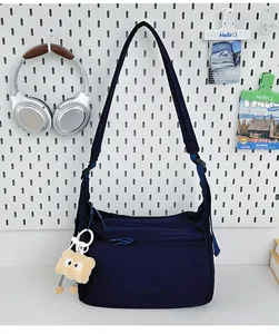 Detail der marineblauen Nylon-Umhängetasche mit Logo und braunem Teddybär-Anhänger