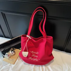 Large red canvas tote bag with white embroidery and leather charm for daily commute
