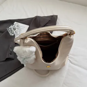 Grand sac fourre-tout crème avec doublure rayée et pendentif ours dans un décor élégant