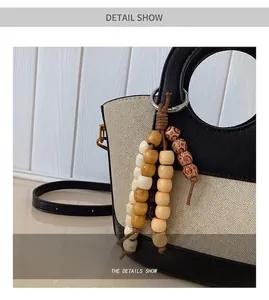 Detail van canvas emmertas met houten kralenhanger en een ronde metalen handgreep