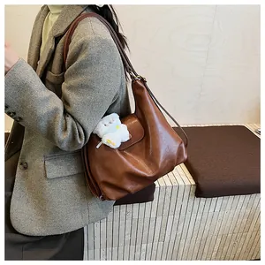 Détail du sac cabas vintage en cuir marron avec pendentif ours en peluche blanc