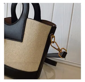 Detailopname van de gouden metalen haak op een bucketbag van canvas en leer
