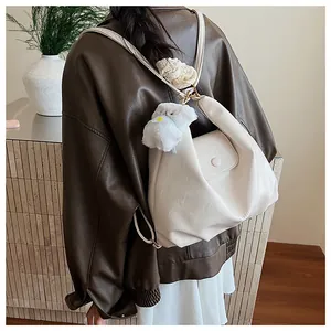 Détail de profil d'un sac à dos blanc en similicuir vintage avec un charme en peluche