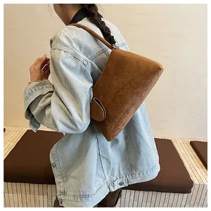 Detail view of the brown faux suede shoulder bag with side buckle on a denim jacket