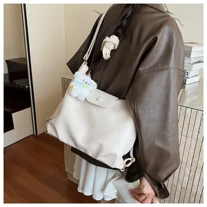 Détail d'un sac à bandoulière blanc crème en simili cuir avec breloque ours en peluche