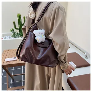 Détail du grand sac cabas en cuir marron foncé avec un pendentif d'ours en peluche doux