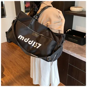 Detail of a large black travel bag with mdd137 logo shown on a person for scale
