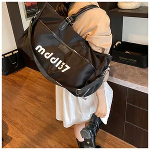 Detail of black large capacity travel bag with white letters and adjustable shoulder strap