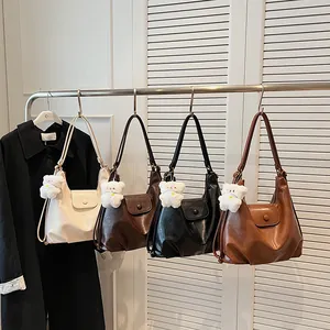 Grands sacs cabas rétro en cuir en quatre couleurs avec breloques d'ours sur rack