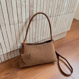 Minimalist brown suede underarm bag with zipper closure and matching charm detail