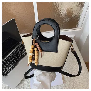 Gedetailleerde weergave van de retro canvas bucket bag met leren contrast en houten kraal
