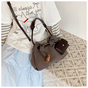 Deep brown canvas bucket bag with drawstring closure and small matching pouch detail