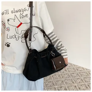 Detail of black canvas bucket bag with brown woven handle and hanging mini pouch
