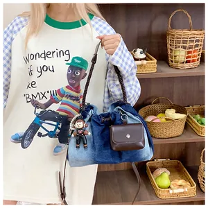 Detail of denim bucket bag featuring woven handle, mini pouch, and cute doll pendant
