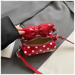 Red polka dot mini cylinder crossbody bag with a large bow detail and silver zipper