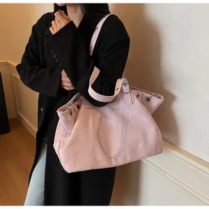 Detailed macro view of a pink suede tote bag featuring metallic eyelets and wide shoulder strap