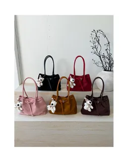 Detail shot of five elegant suede tote bags in assorted colors with plush bear charms
