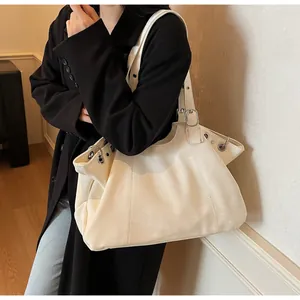 Close-up of cream PU leather tote bag featuring metallic eyelets and adjustable strap detail