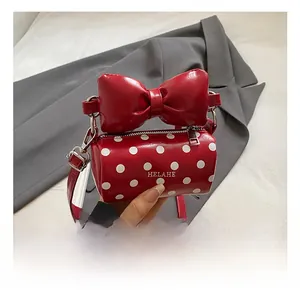 Detailed macro view of a red polka dot mini bag featuring a large bow and silver zipper