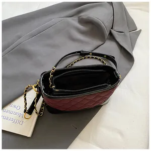 Vintage burgundy quilted bucket bag with gold chain strap on grey blazer