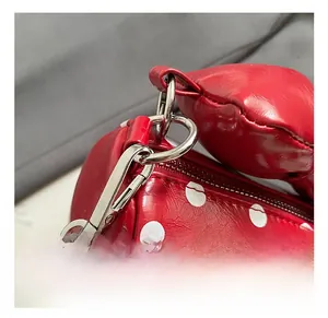 Macro view of red polka dot bag with silver hook, zipper, and heart pendant detail