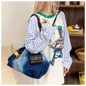 Detail of gradient blue denim tote bag with leather handles and a small hanging pouch