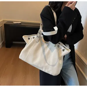 Detailed close-up of large minimalist cream tote bag with silver eyelets and buckle strap