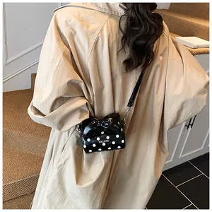 Detailed back view of a mini polka dot bag with a large bow worn over a beige trench coat