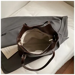 Minimalist large brown leather tote bag with zip closure and spacious interior lining