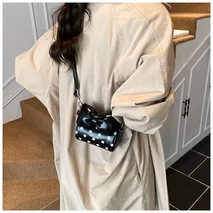 Detailed view of the mini polka dot bag with a large bow on an elegant trench coat