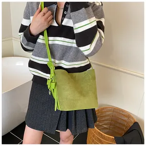 Detail of green frosted suede bucket bag with slim leather strap and decorative pendant