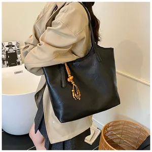 Detailed side view of large black matte tote bag with decorative wooden bead tassel