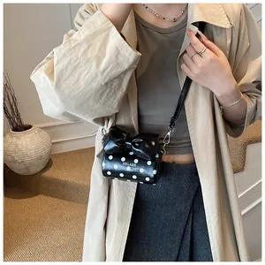 Polka dot mini crossbody bag with a large bow detail shown on a model outfit