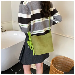 Light green suede hobo bag shown on shoulder with elegant side bow detail