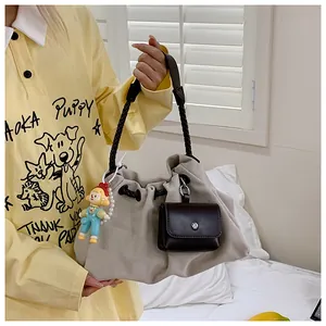 Detail of a large khaki canvas tote bag with brown braided strap and colorful pendants