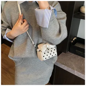 Close-up of a mini white polka dot bag with a bow detail and metal strap hooks