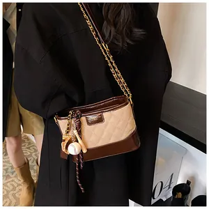 Detail of retro quilted bucket bag with shiny brown leather and baseball charms