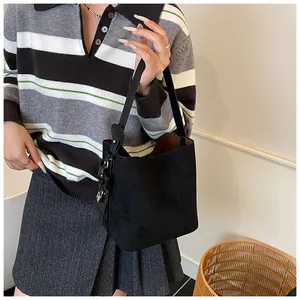 Detail of black matte suede bucket bag showing metallic buckle and textured strap