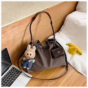 Detail of canvas tote bag with drawstring texture, woven strap and plush doll pendant