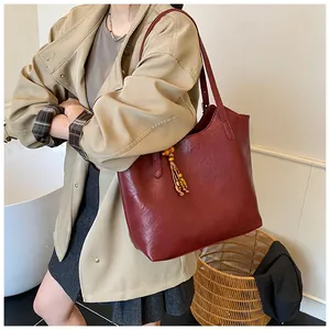 Detail of dark red tote bag with wood bead tassel charm and textured PU leather finish