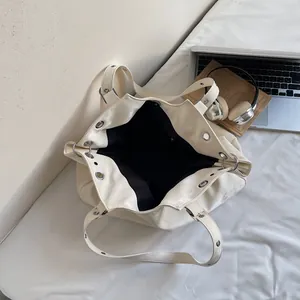 Minimalist cream tote bag with silver metal eyelets and large interior capacity