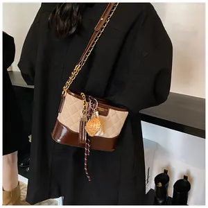 Detail of quilted bucket bag featuring a color-block design and chic strawberry charm